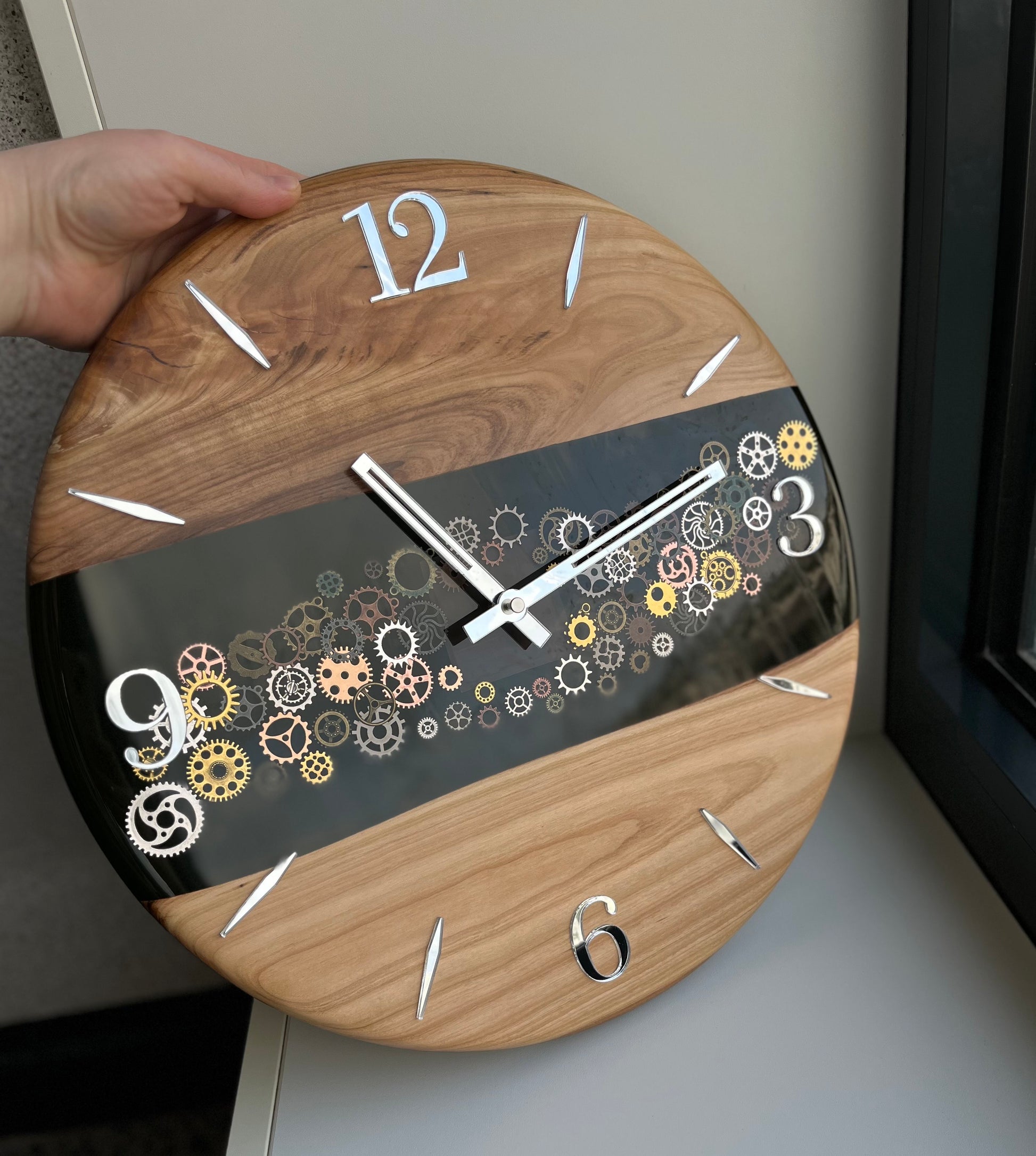 Handcrafted wall clock combining epoxy resin and cherry wood, featuring visible gears and precise silent movement.