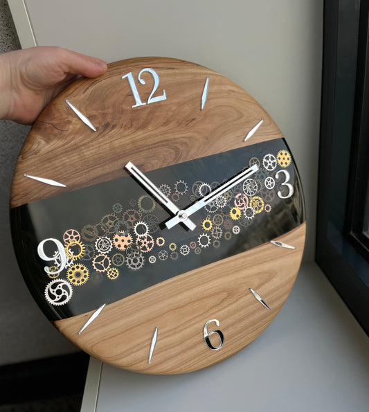 Handcrafted wall clock combining epoxy resin and cherry wood, featuring visible gears and precise silent movement.